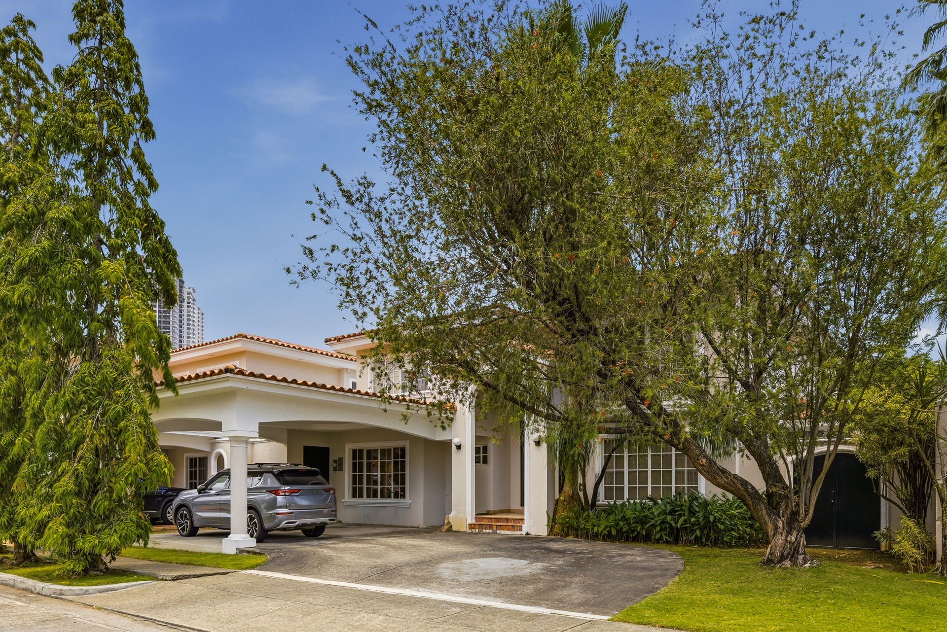 Fachada principal de residencia de lujo en Costa Bay, Costa del Este, con arquitectura mediterránea y vegetación madura — proyecto conjunto de tour virtual, plano de planta y fotografía profesional en Panamá.