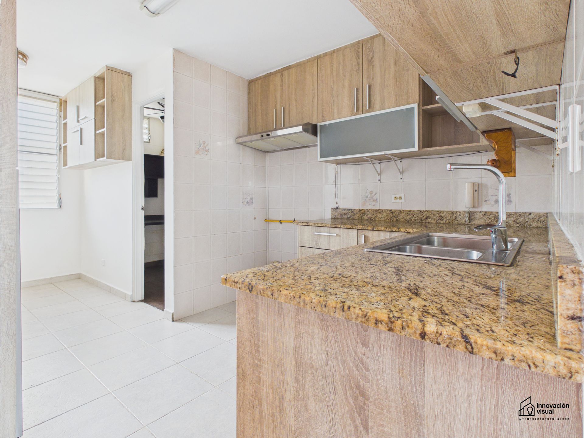 Una cocina con gabinetes de madera clara, encimeras de granito y fregadero de acero inoxidable.