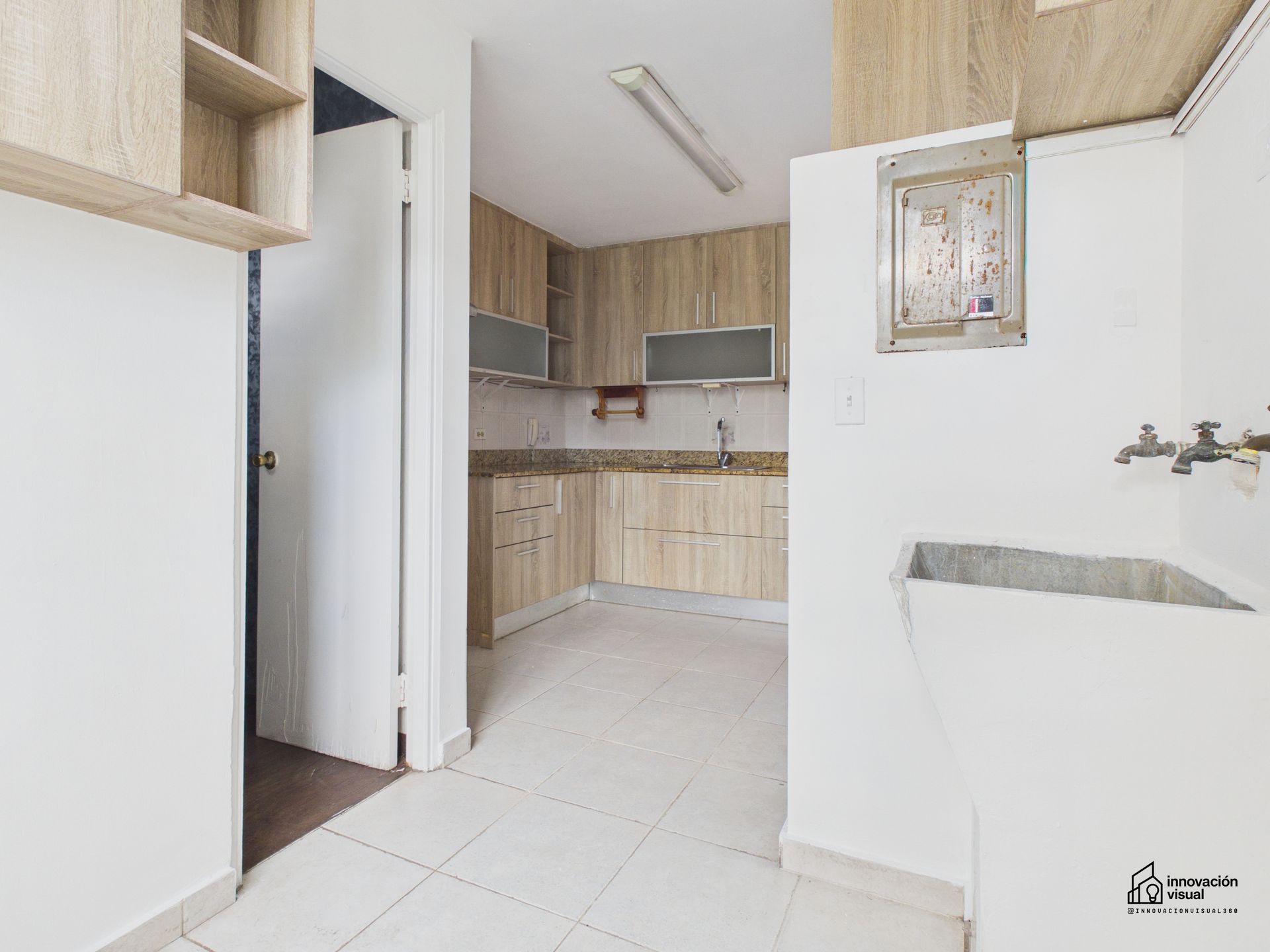 Cocina con gabinetes de madera clara, piso de baldosas y fregadero.