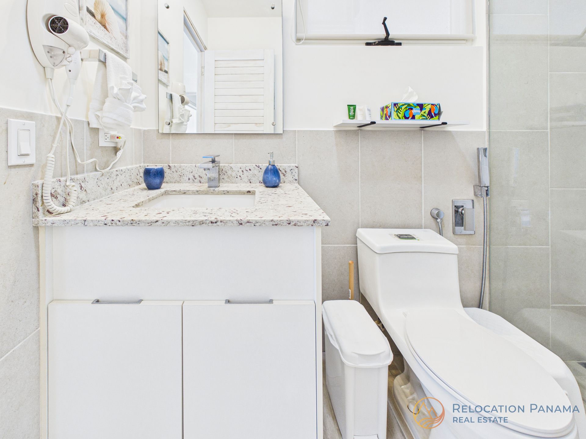 Baño blanco brillante con lavabo, inodoro, bidé y ducha sobre paredes alicatadas.