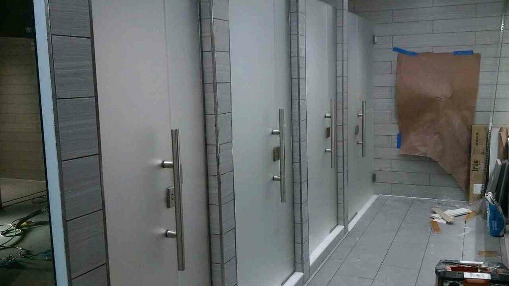 Row of white restroom stalls in a tiled public bathroom, with a brown paper covering one stall door.