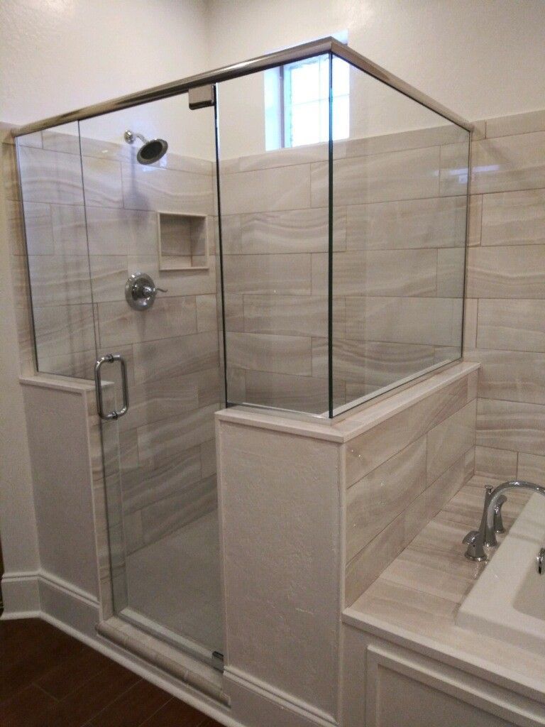 Glass shower enclosure with chrome fixtures and beige tile in a bathroom