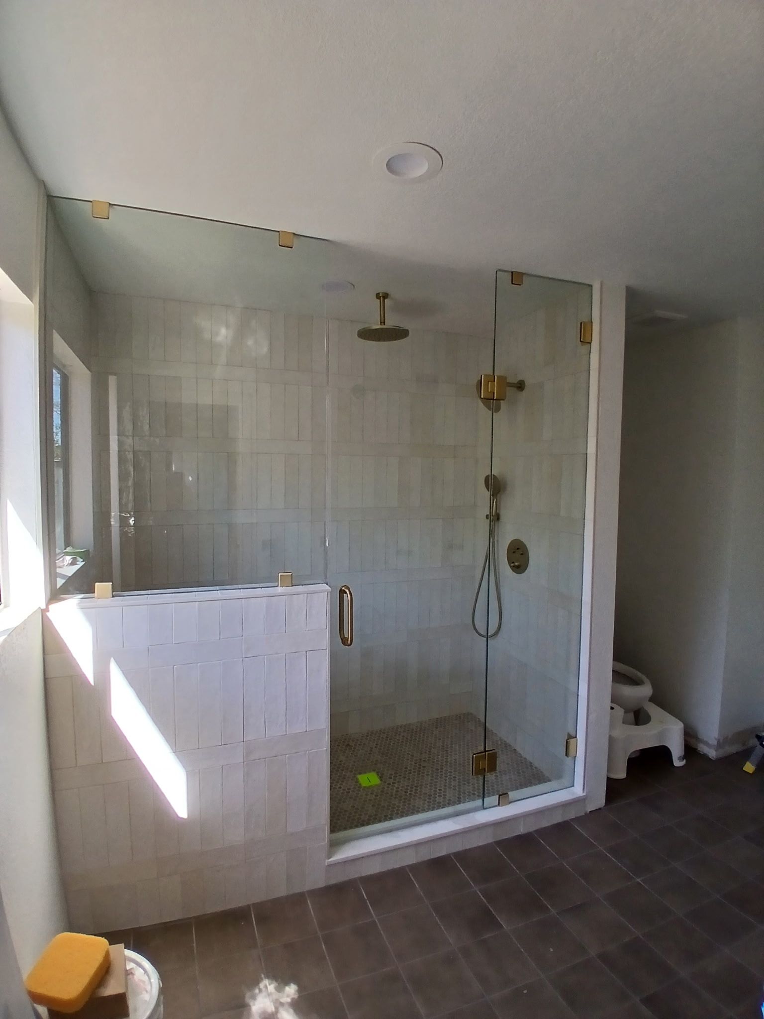 Empty bathroom with a glass-enclosed shower, white tiled walls, and dark floor tiles.