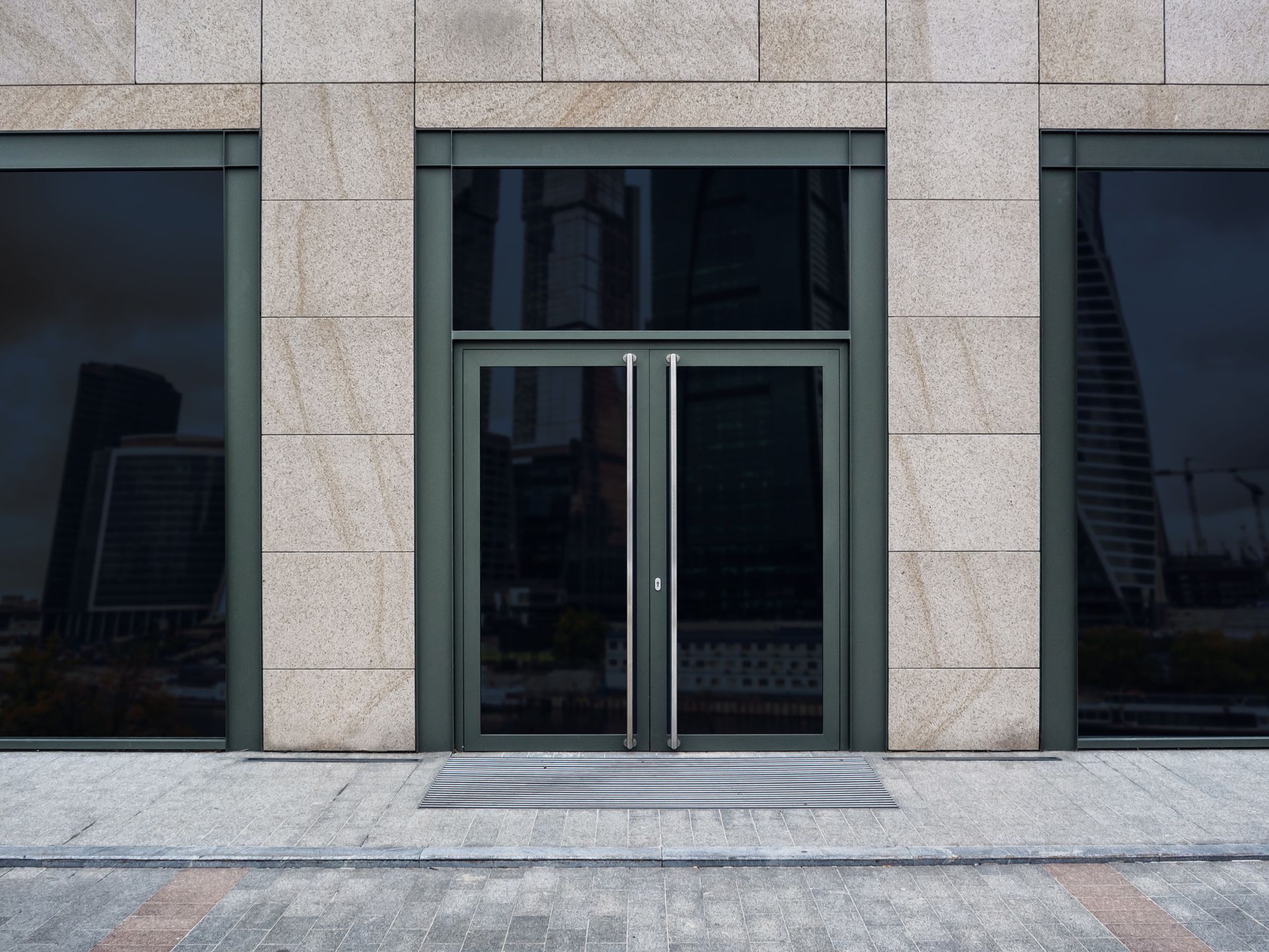 Modern glass office entrance with double doors and stone facade