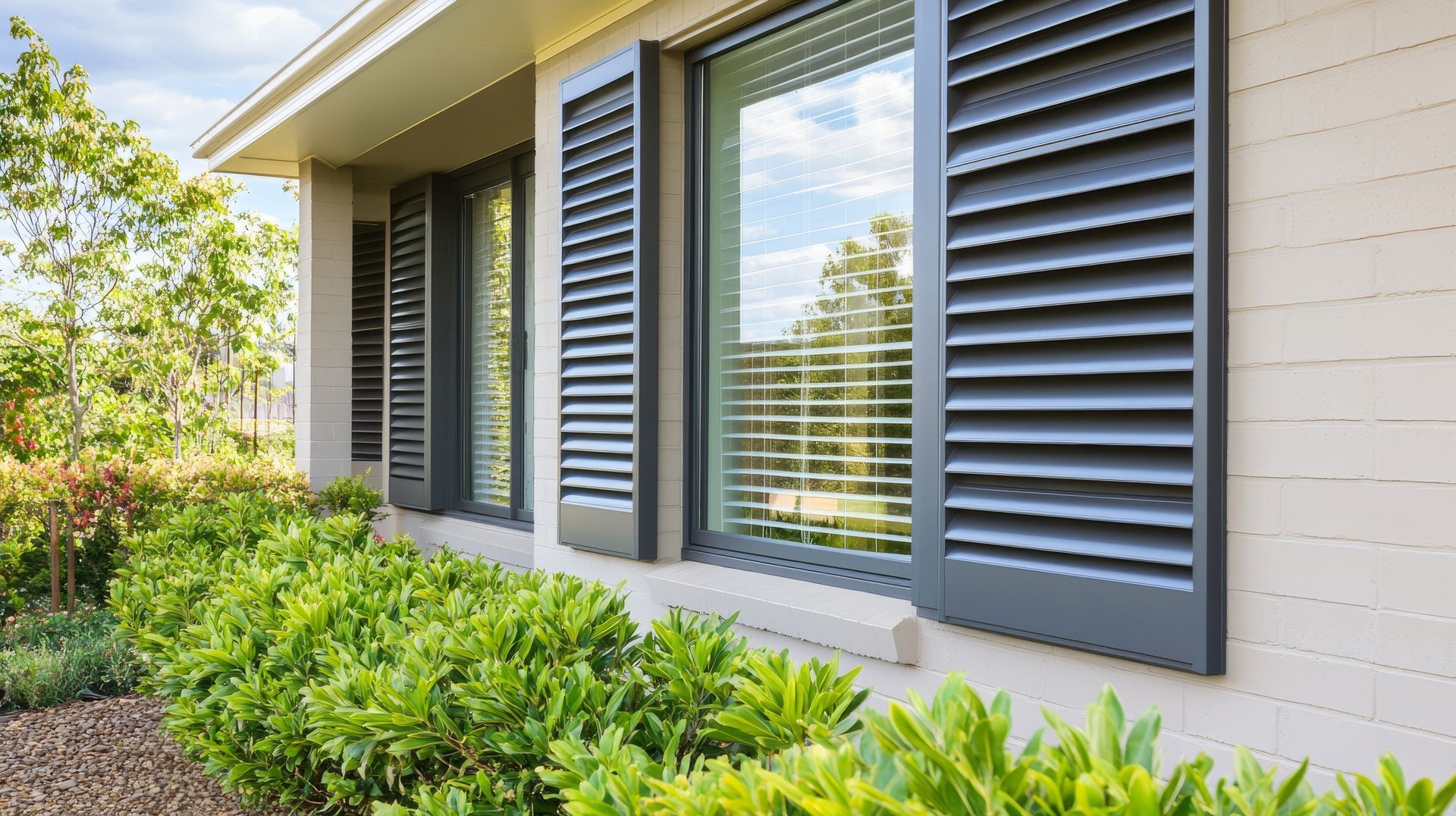 Modern house exterior with dark gray louvered shutters and green landscaping