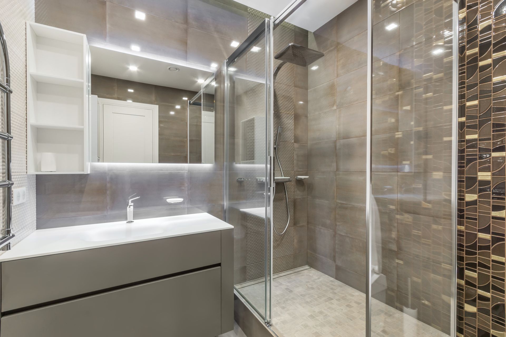 Modern bathroom with white vanity, large mirror, glass shower, and beige tile walls