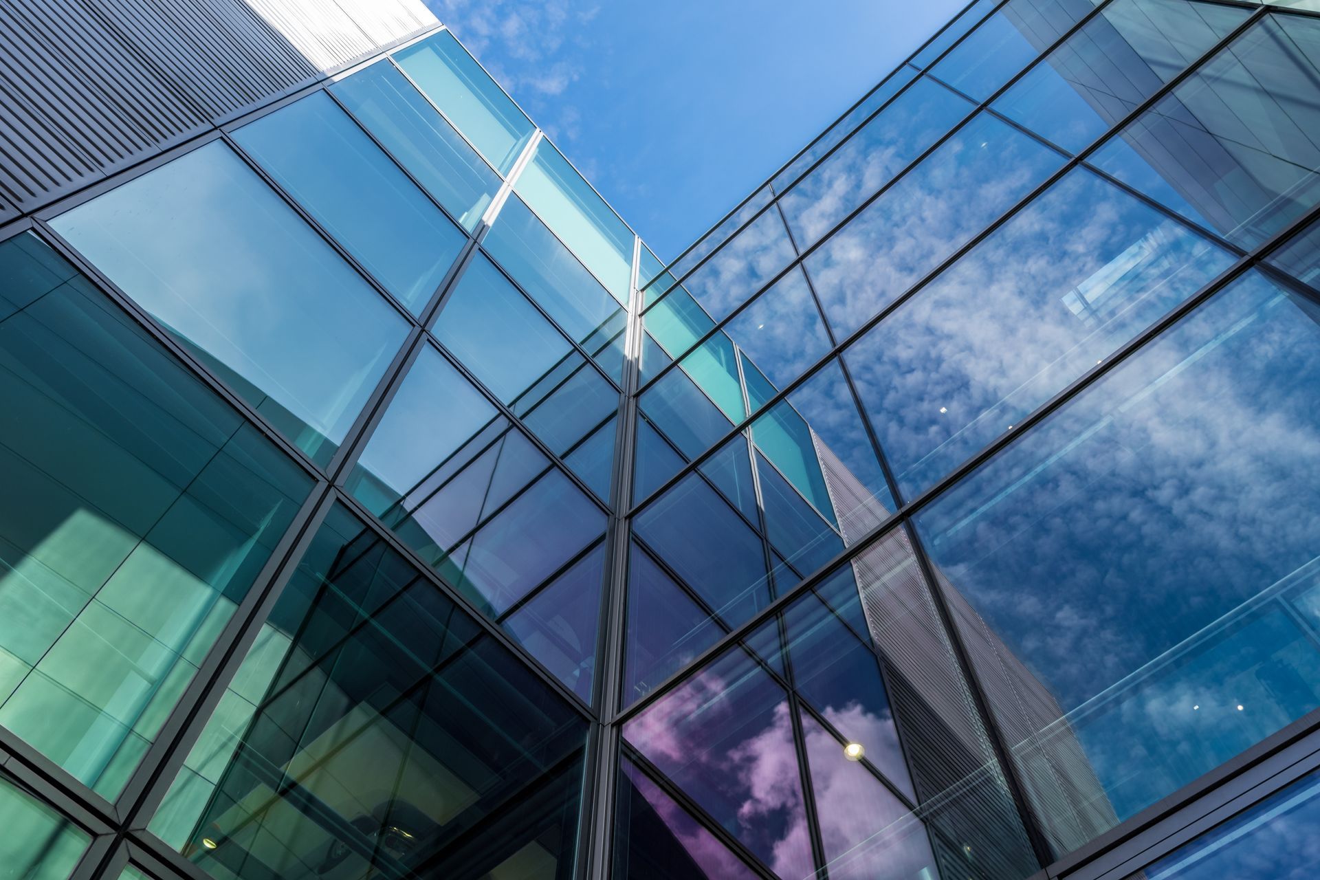 Glass office building with blue reflective windows and steel frames against the sky