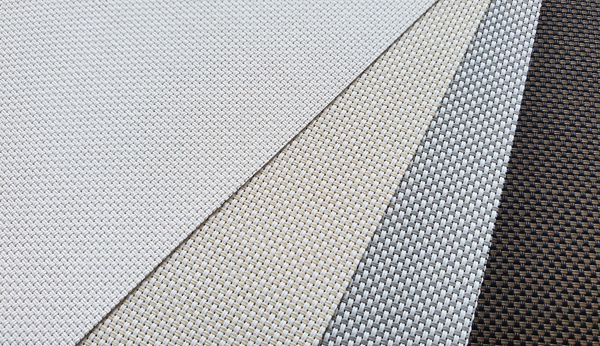 Overlapping textured fabric swatches in light gray, beige, white, and dark charcoal tones