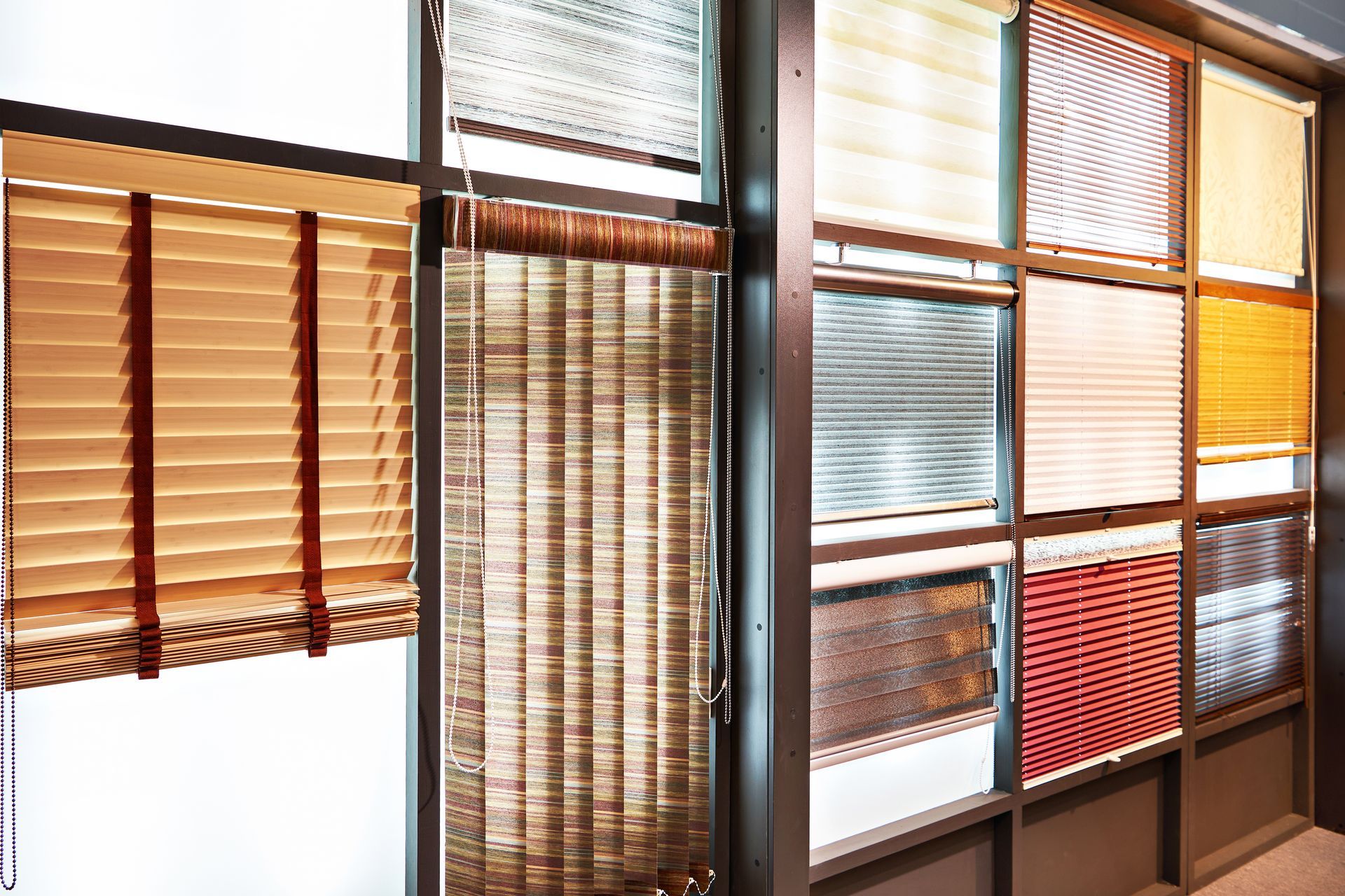 Interior window display of assorted wooden and fabric blinds in brown, tan, white, and red