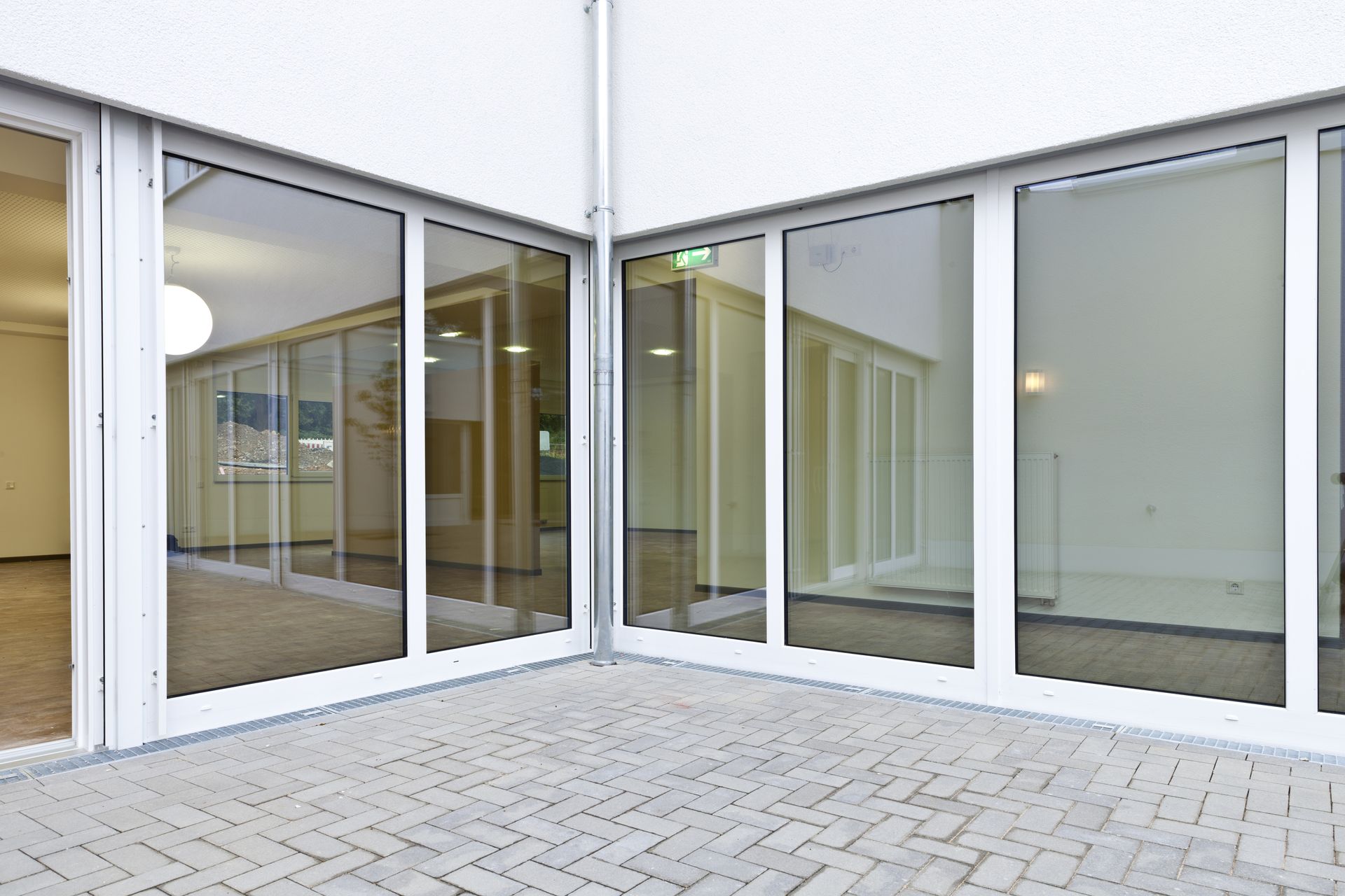 Empty glass-fronted patio or storefront with white walls and a paved courtyard