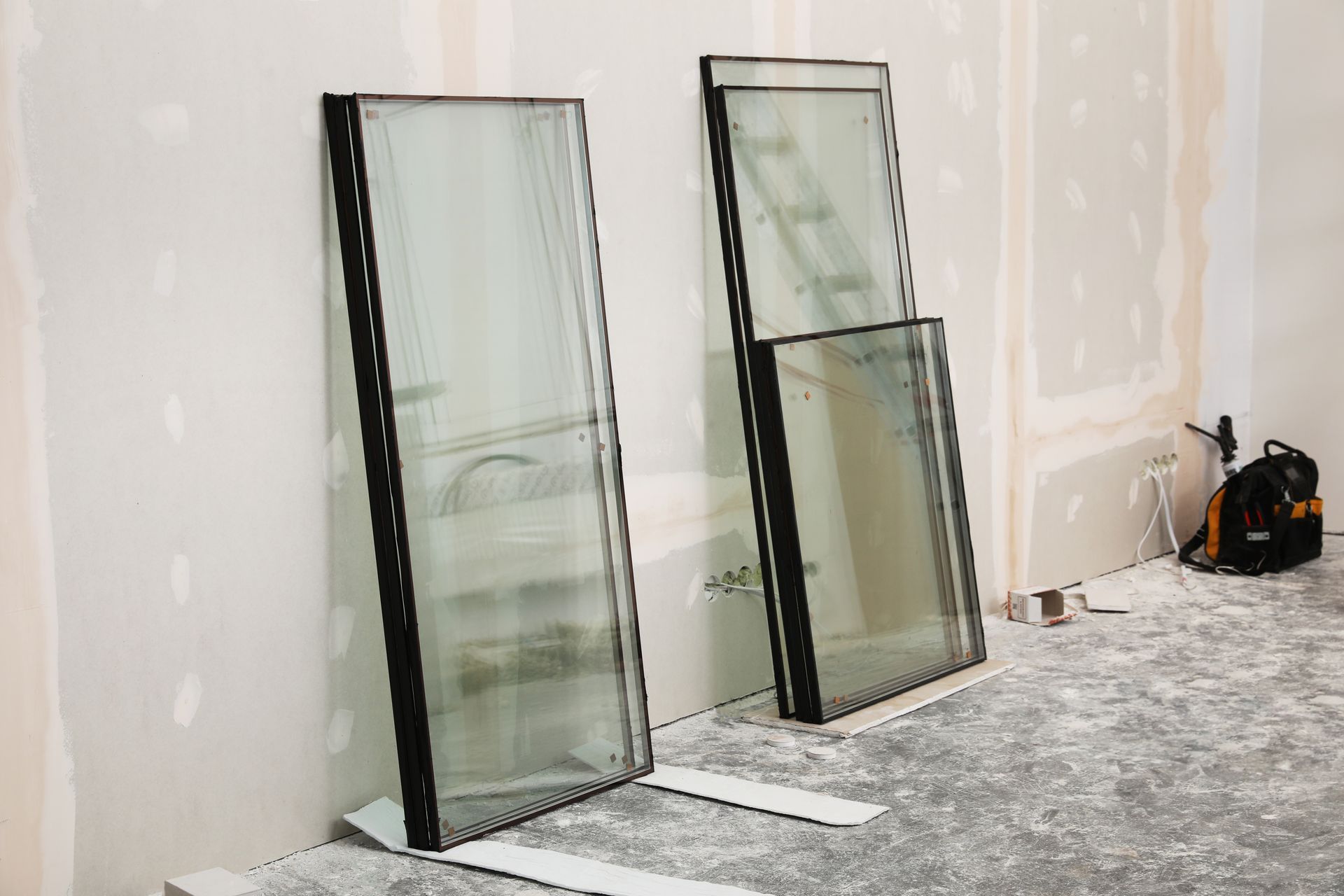 Two large glass panels leaning against a wall in a partially finished room.