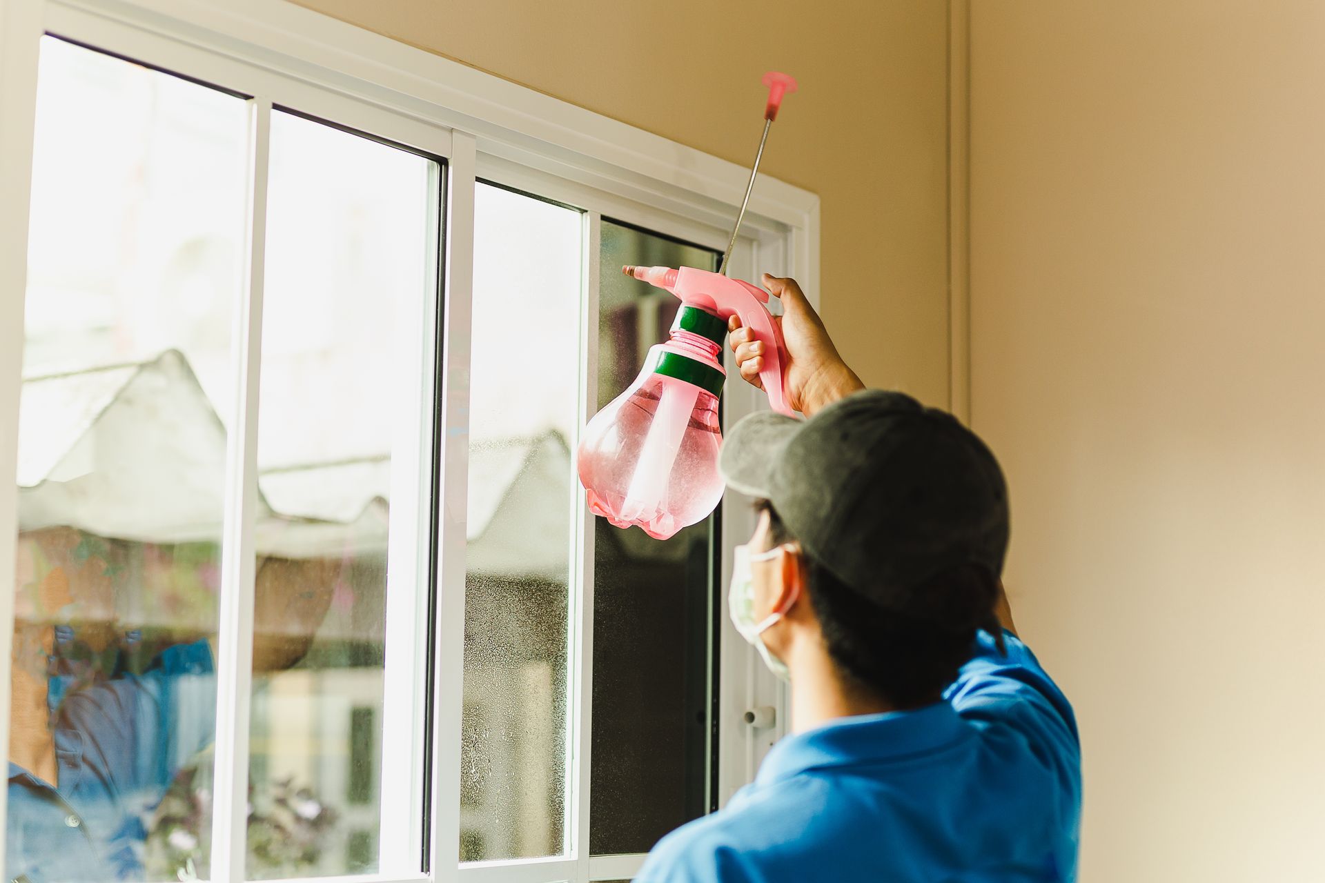Person cleaning a window with a pink cloth and spray bottle indoors