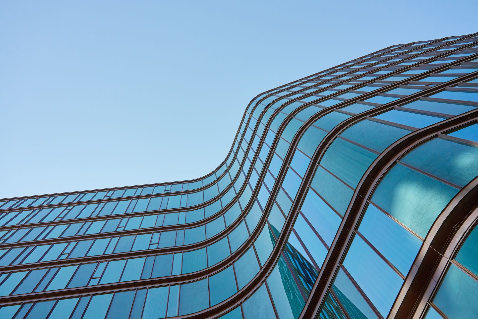 Curved glass office building with blue reflective windows against a clear sky