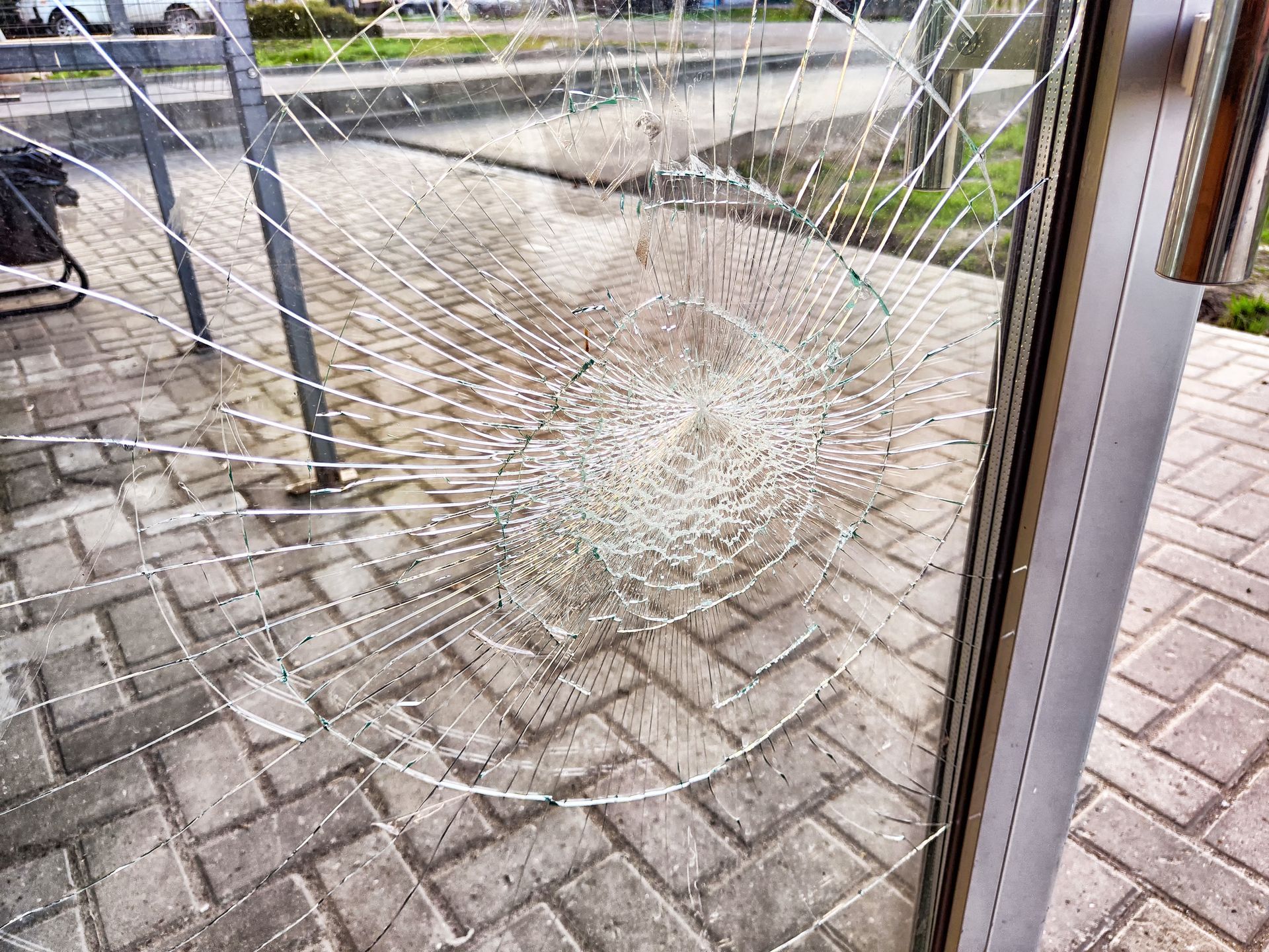 Broken glass pane in a metal frame over a brick patio and garden fence
