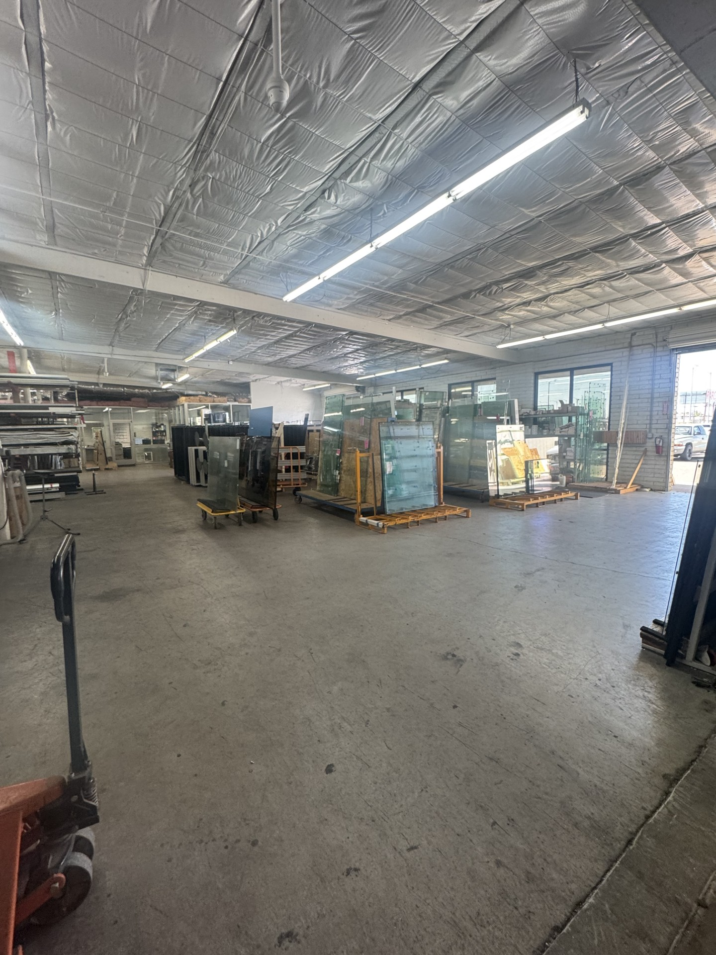 Empty industrial warehouse interior with orange cones, metal shelving, and fluorescent ceiling lights