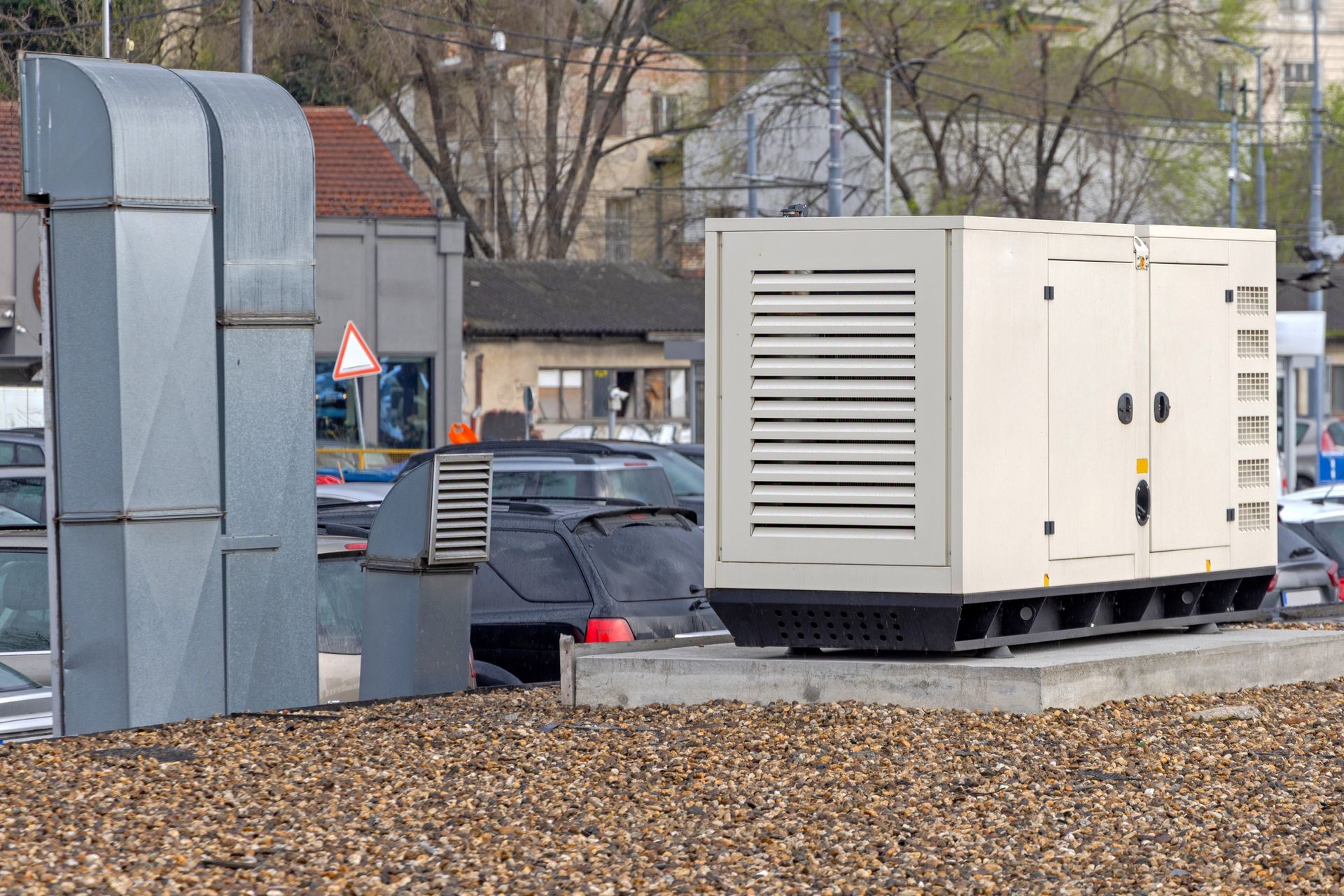 Generator in an industrial setting, beige enclosure with ventilation, next to ductwork.