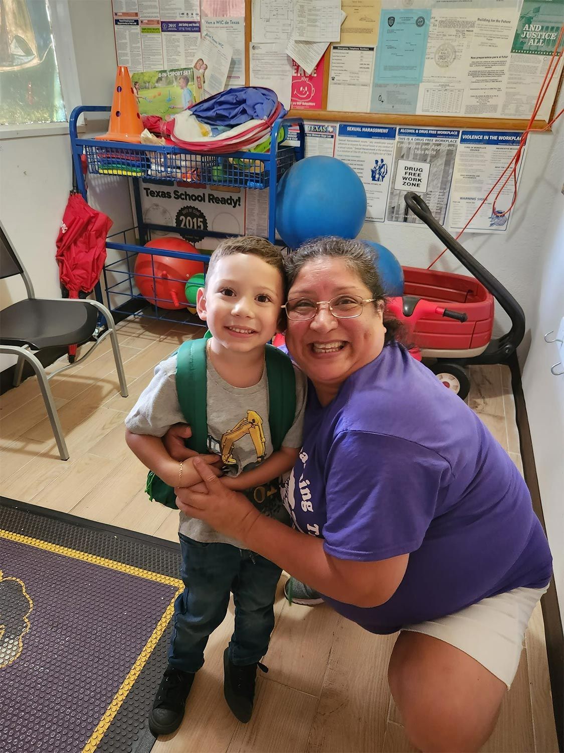 Smiling woman hugging the child in a classroom