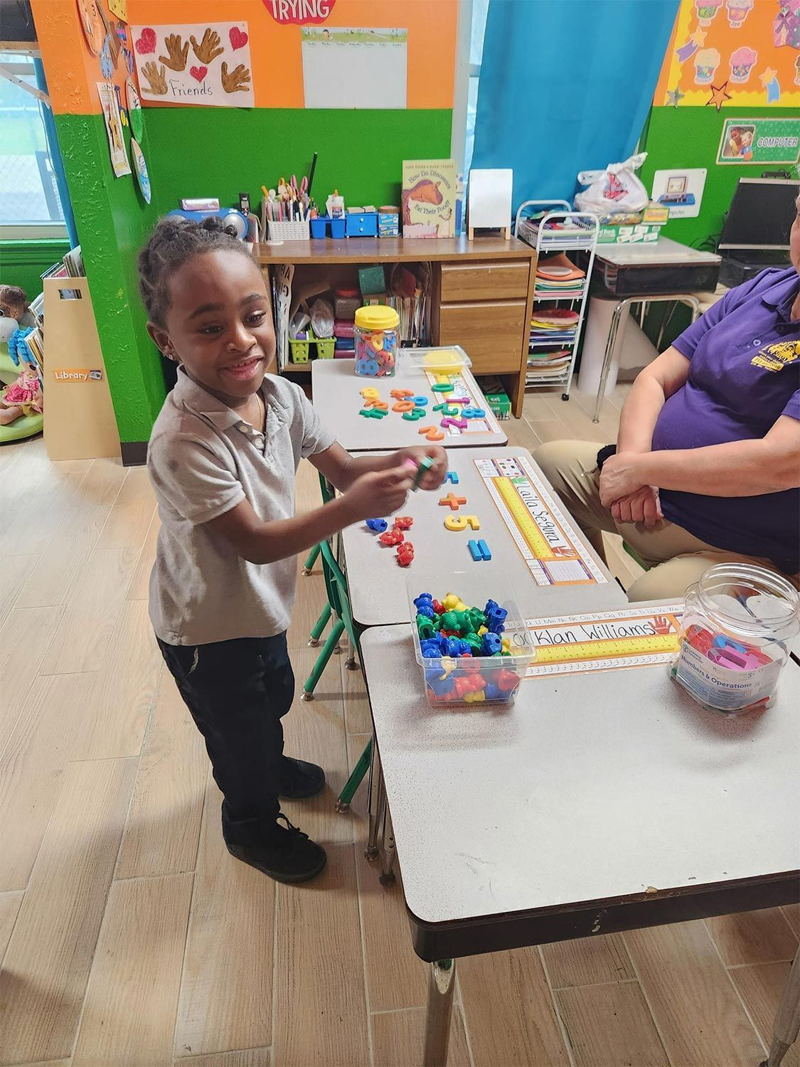 Child playing with numbers at a classroom table
