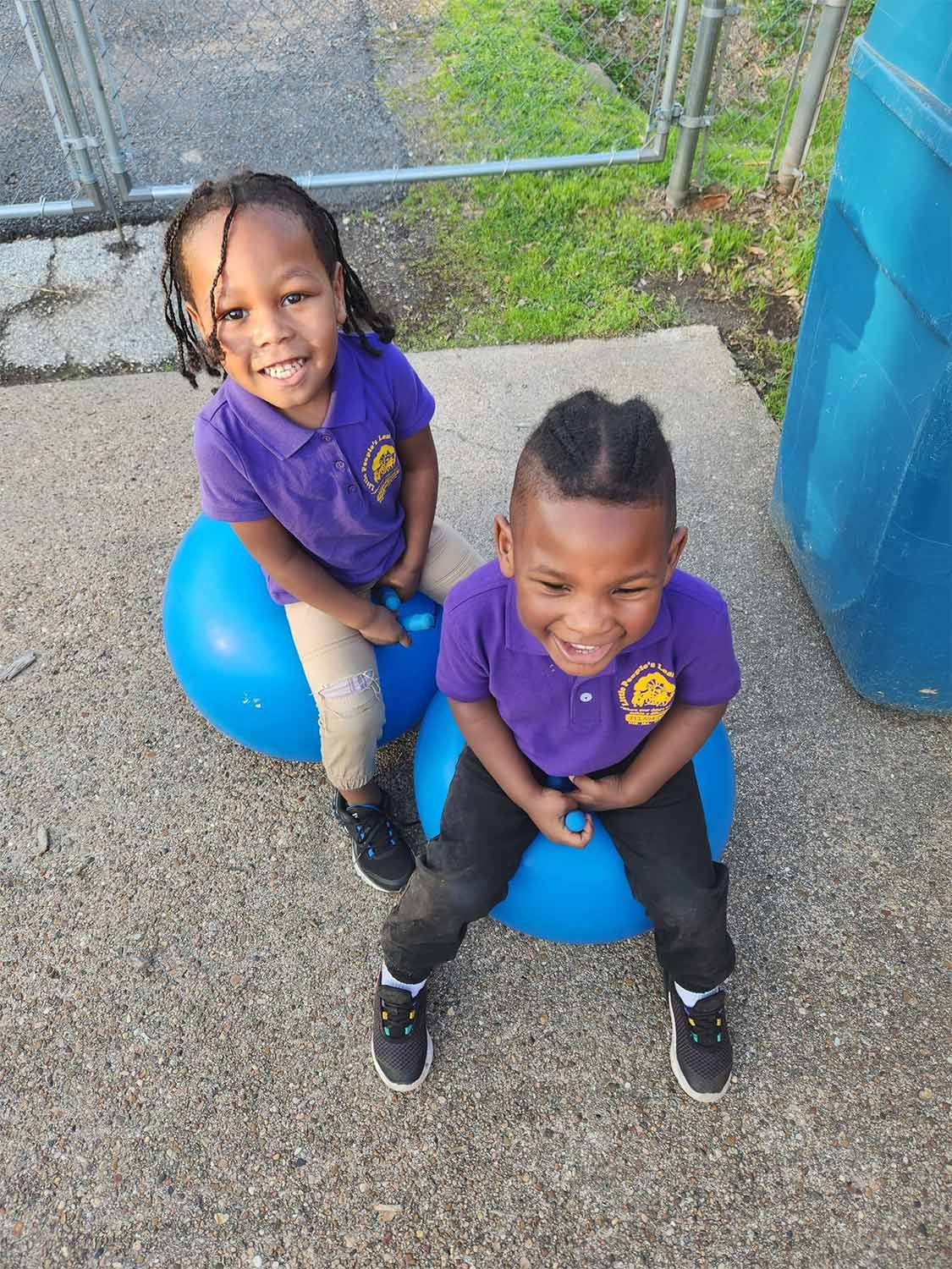 Children sitting on blue balls in backyard