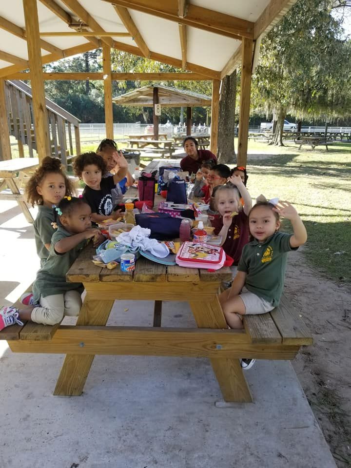Children gathered at a picnic table under a wooden pavilion