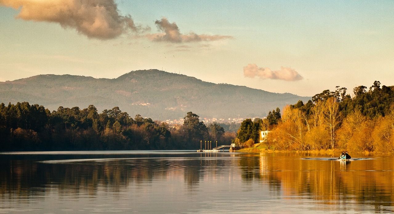 Um lago com montanhas ao fundo e árvores na margem.