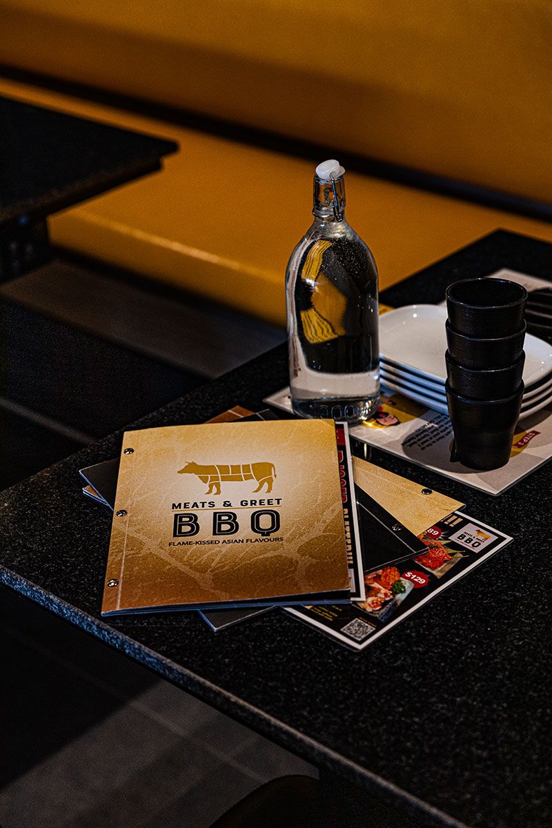 Table With a Yellow Menu Lying Next to a Glass Bottle — JMB Electrical Services In Port Kembla, NSW