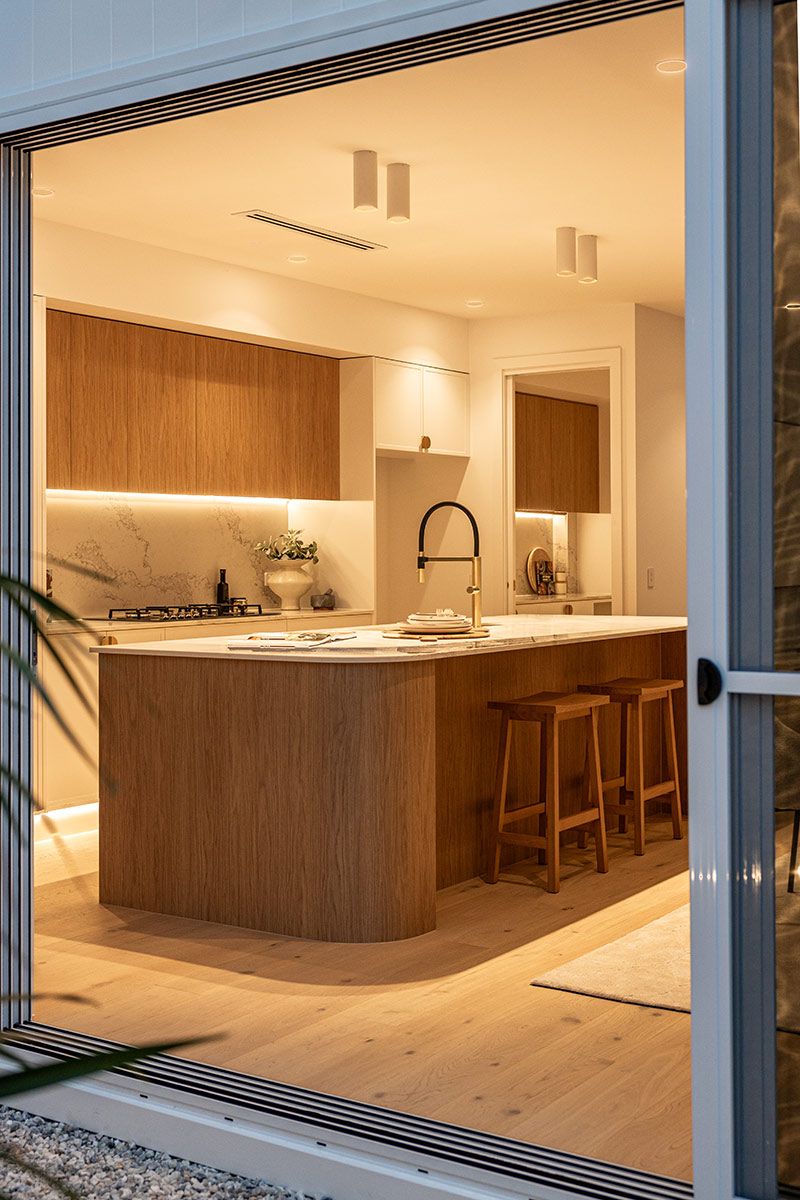 A Kitchen With a Large Island and Stools — JMB Electrical Services In Port Kembla, NSW