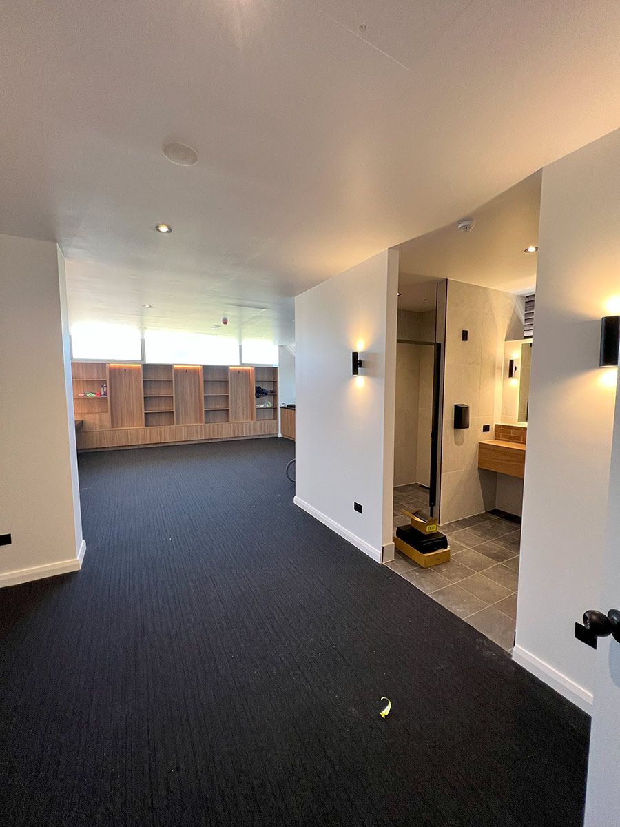 Modern Room With Built-in Wooden Shelves and a Small Open Bathroom — JMB Electrical Services In Port Kembla, NSW