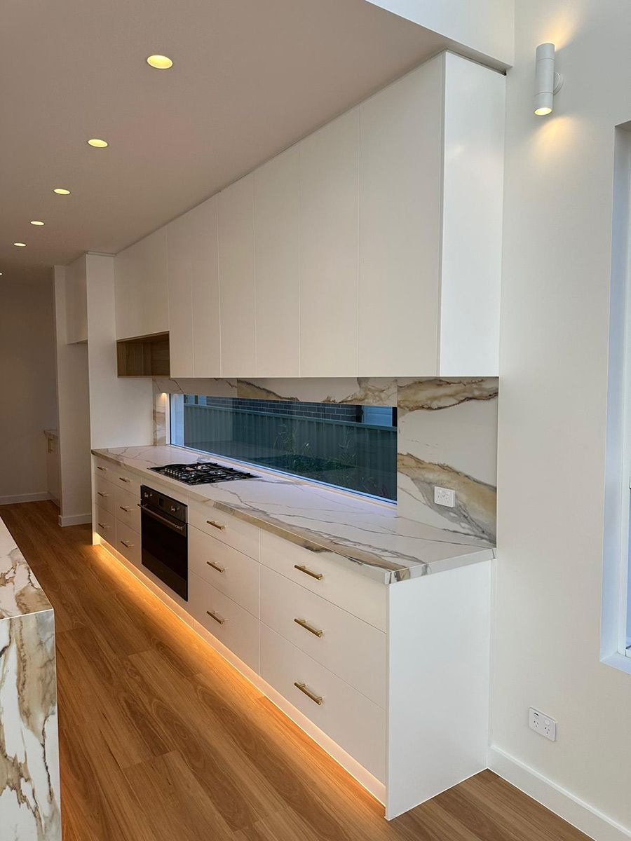 Modern Kitchen Featuring Marble Countertops and Wood Flooring — JMB Electrical Services In Port Kembla, NSW