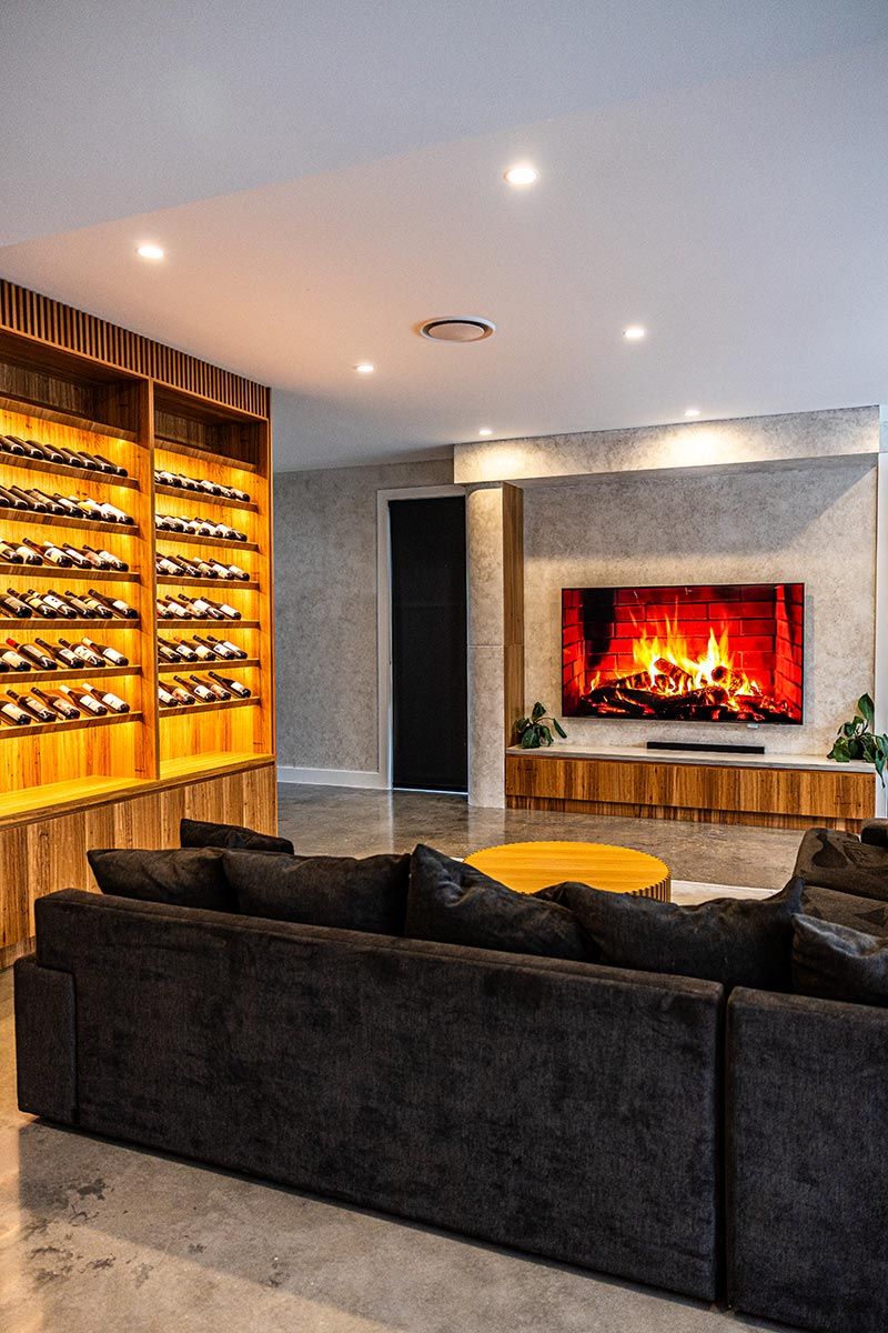 Living Room With a Dark Sofa and a Wooden Wine Rack — JMB Electrical Services In Port Kembla, NSW