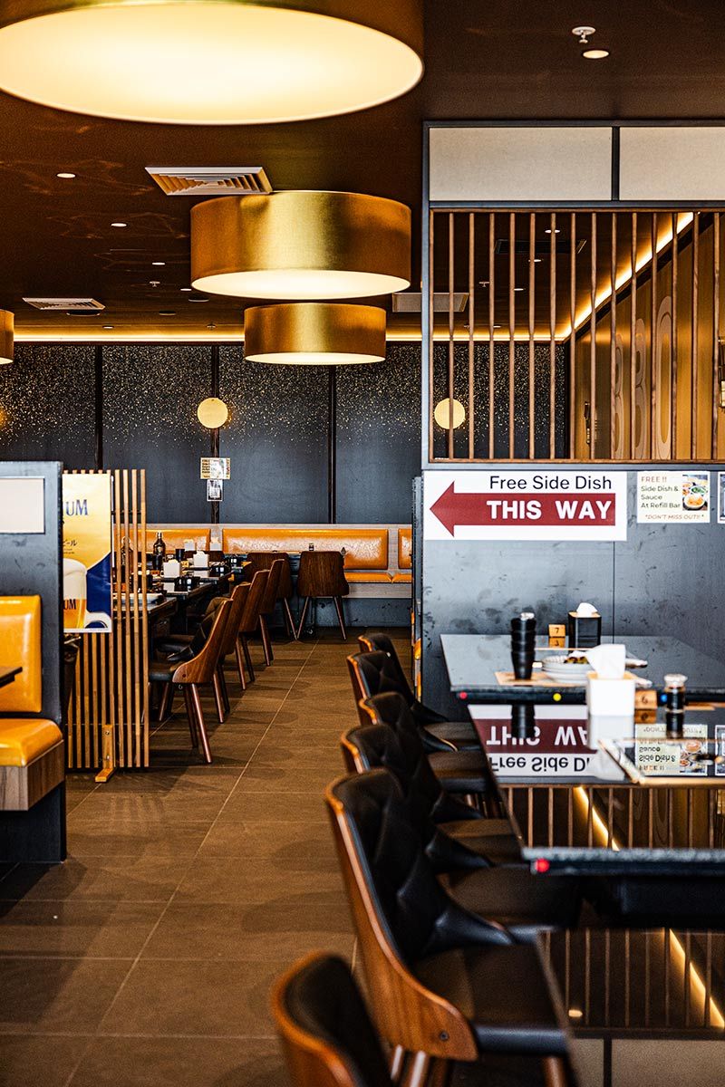 Modern Restaurant Interior With Wooden Chairs and a Sign — JMB Electrical Services In Port Kembla, NSW