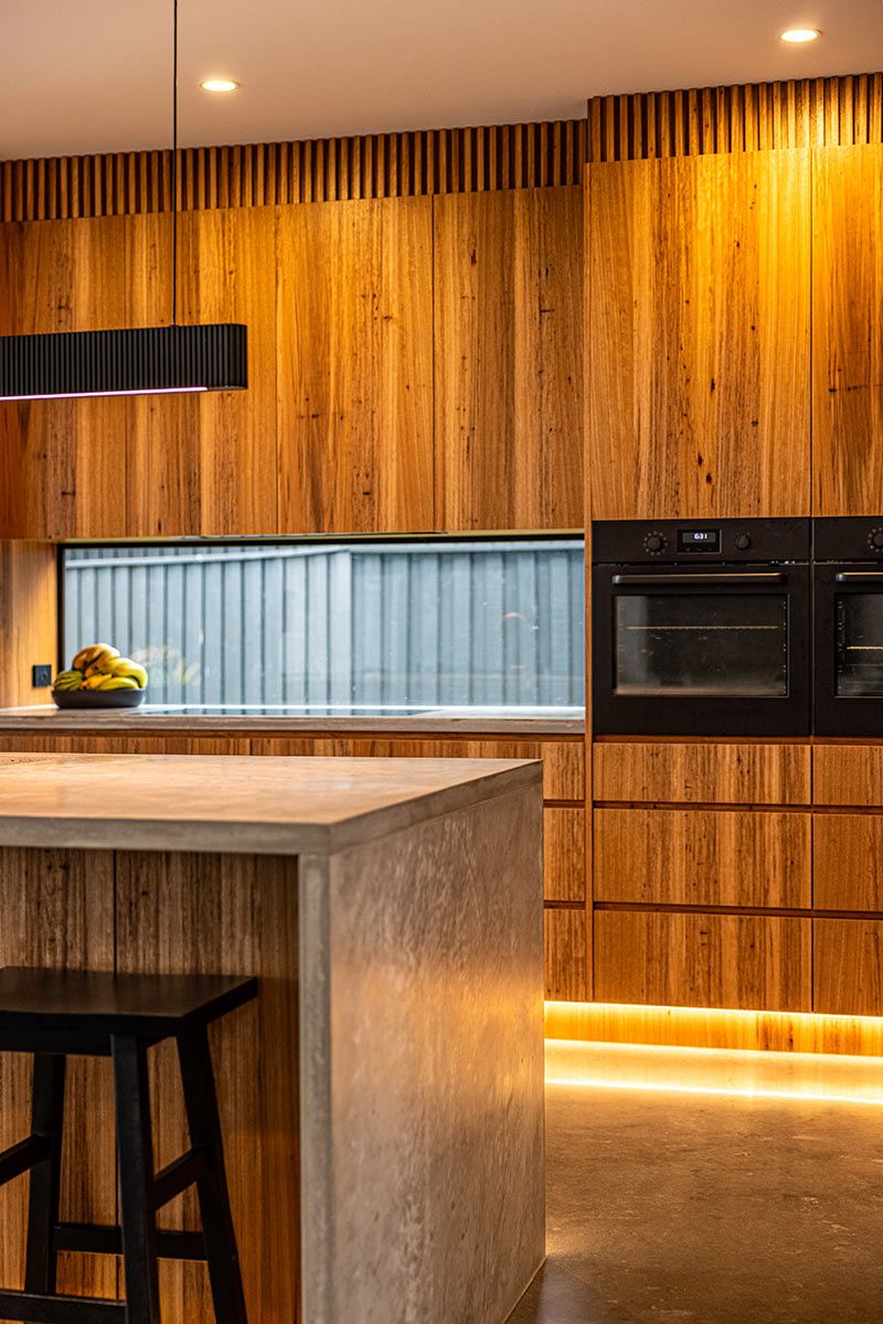 Modern Kitchen With Warm Wooden Cabinetry and a Concrete Island — JMB Electrical Services In Port Kembla, NSW