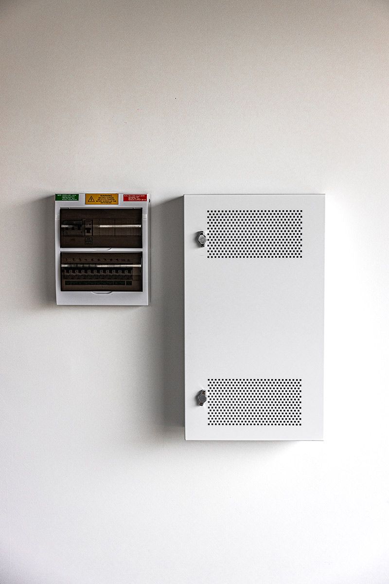 A White Wall With Two Electrical Panels Mounted — JMB Electrical Services In Port Kembla, NSW