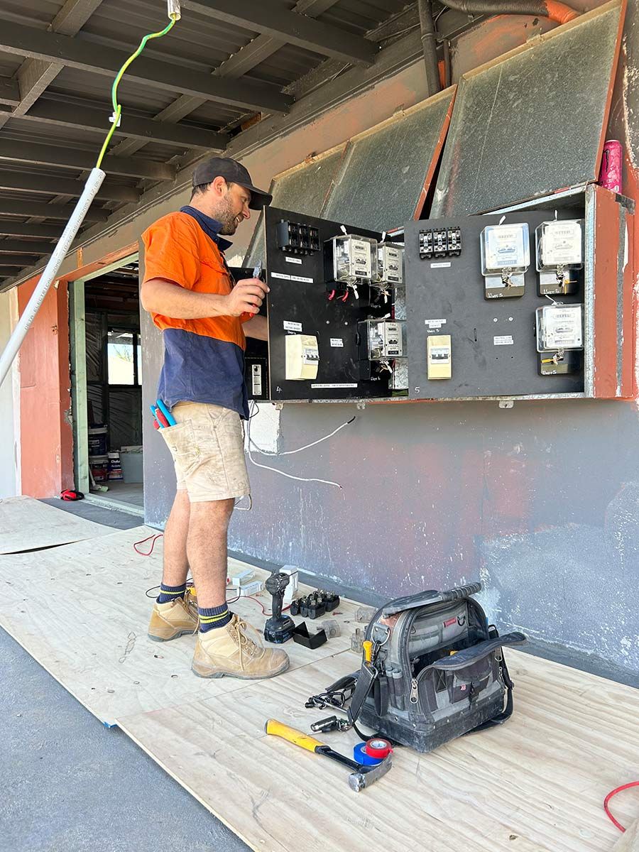 A Man Examines an Electrical Panel — JMB Electrical Services In Port Kembla, NSW