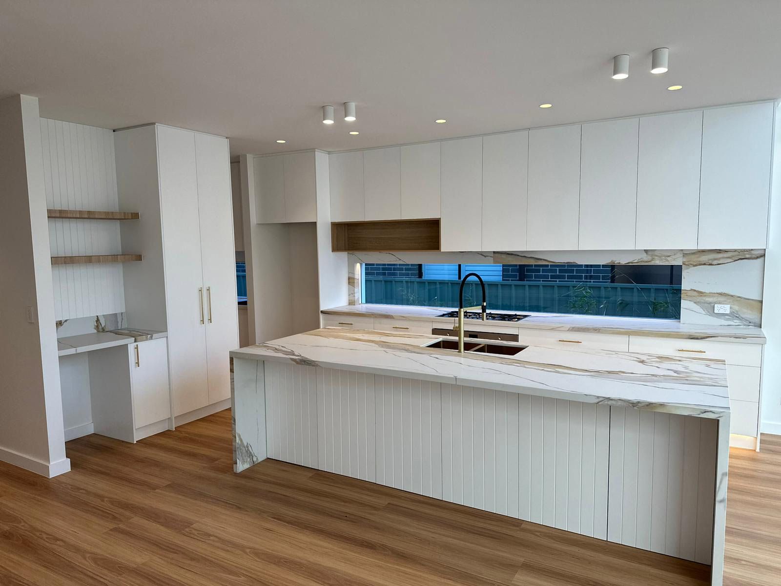Modern Kitchen With White Cabinets and a Large Marble Island — JMB Electrical Services In Port Kembla, NSW