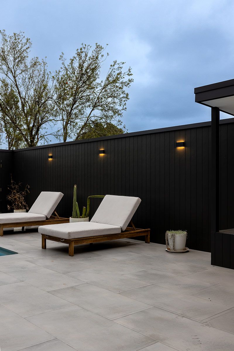 Outdoor Patio With Two White Cushioned Wooden Loungers — JMB Electrical Services In Port Kembla, NSW