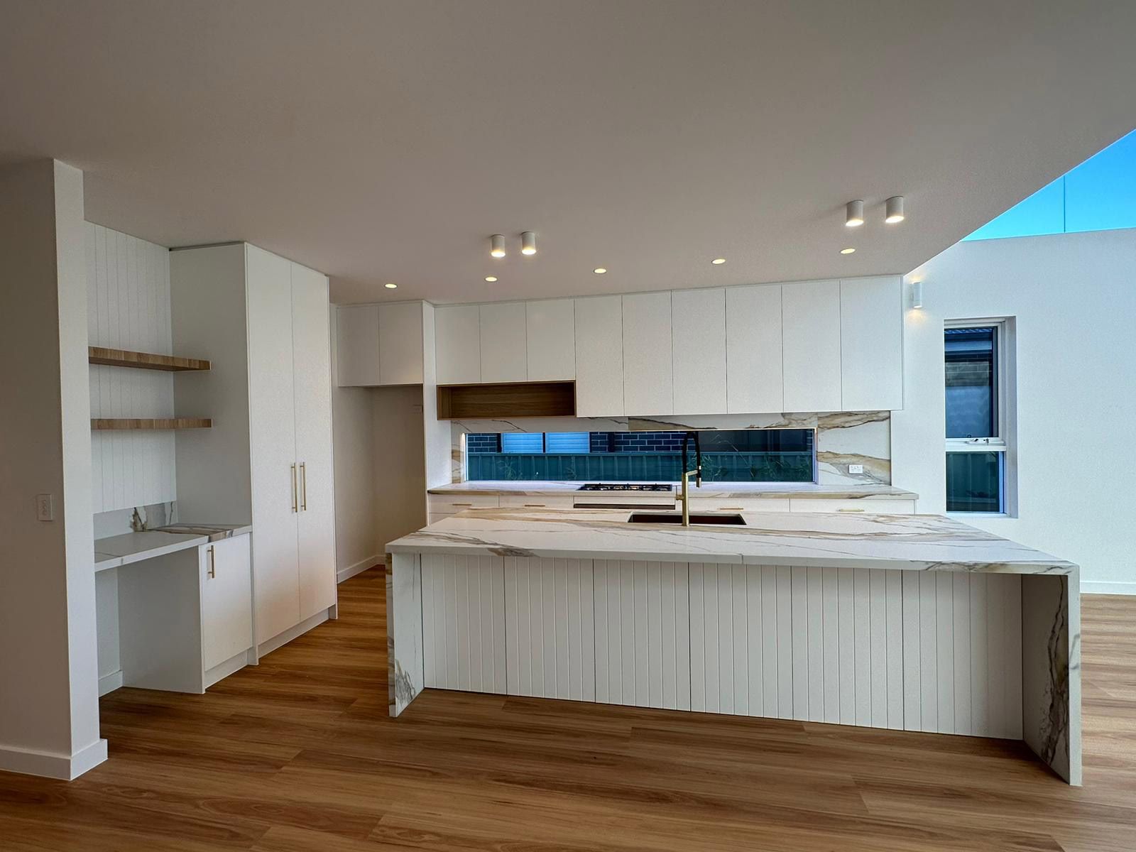 Modern Kitchen With a Large Marble Island and Wooden Floors — JMB Electrical Services In Port Kembla, NSW