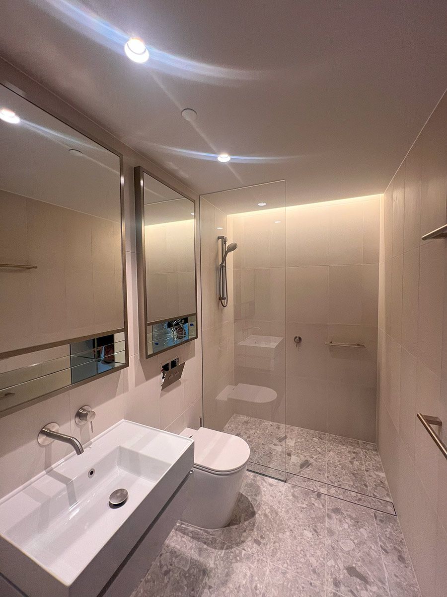 A Modern Bathroom With a Wall-mounted Sink and Toilet — JMB Electrical Services In Port Kembla, NSW