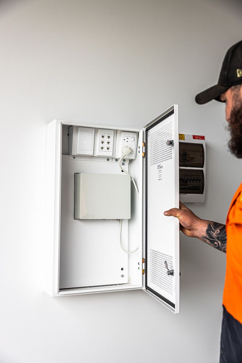 A Man Opens an Electrical Control Panel — JMB Electrical Services In Port Kembla, NSW