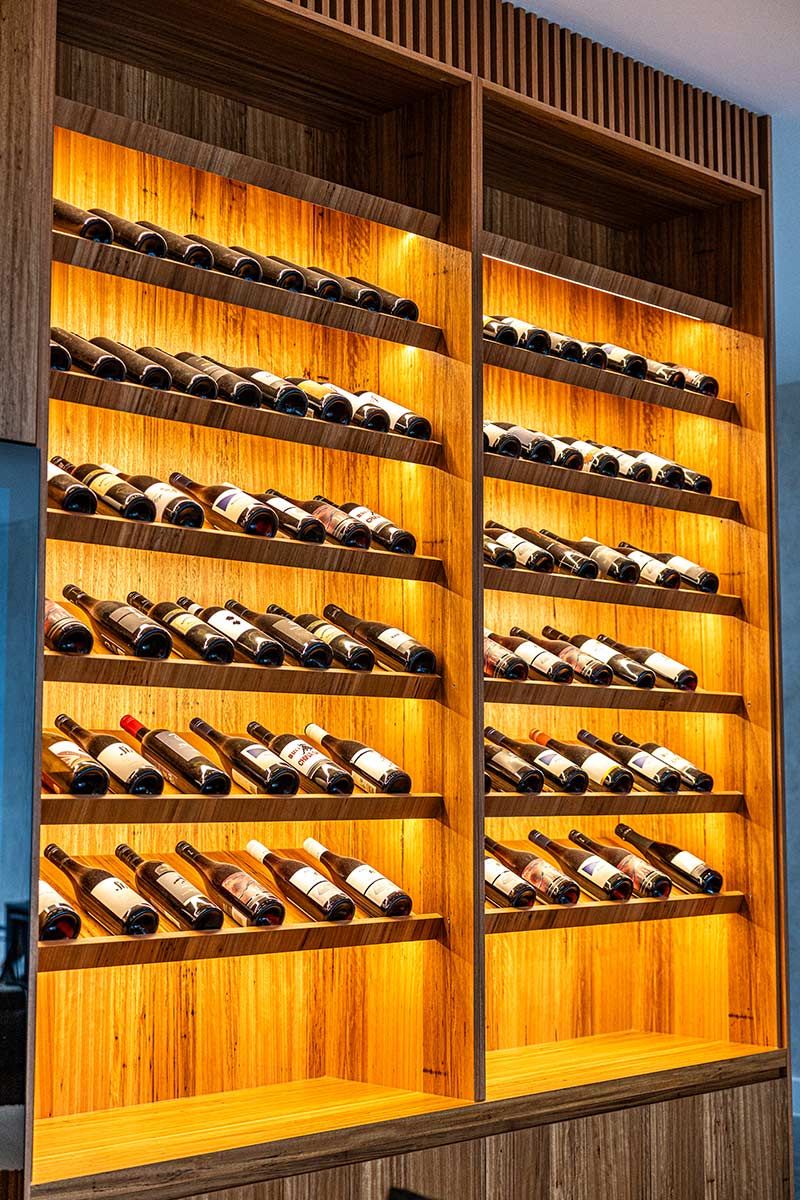 A Wooden Wine Rack Filled With Bottles — JMB Electrical Services In Port Kembla, NSW