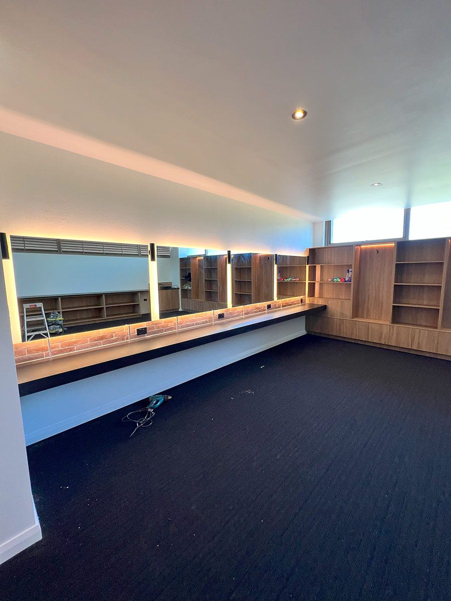 Spacious Room With Black Carpet and Wooden Shelves — JMB Electrical Services In Port Kembla, NSW