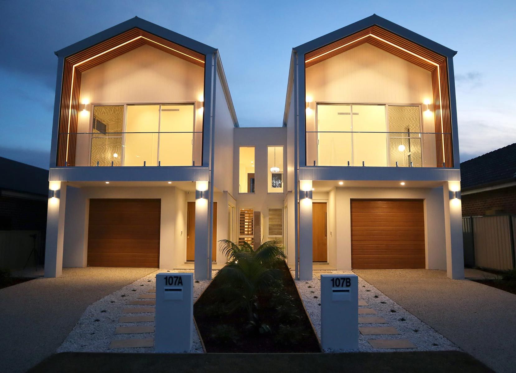 Twin Townhouses With Wooden Garage Doors and Upper-level Glass Balconies — JMB Electrical Services In Port Kembla, NSW