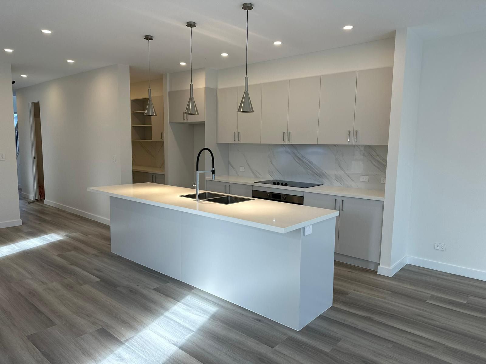 Modern Kitchen With a Sleek Island and White Countertops — JMB Electrical Services In Port Kembla, NSW