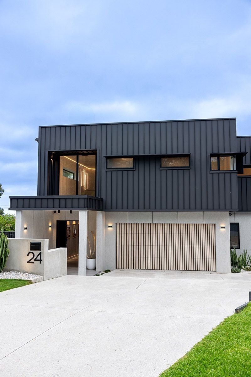House With Dark Paneling, Large Windows, and Wooden Garage Door — JMB Electrical Services In Port Kembla, NSW