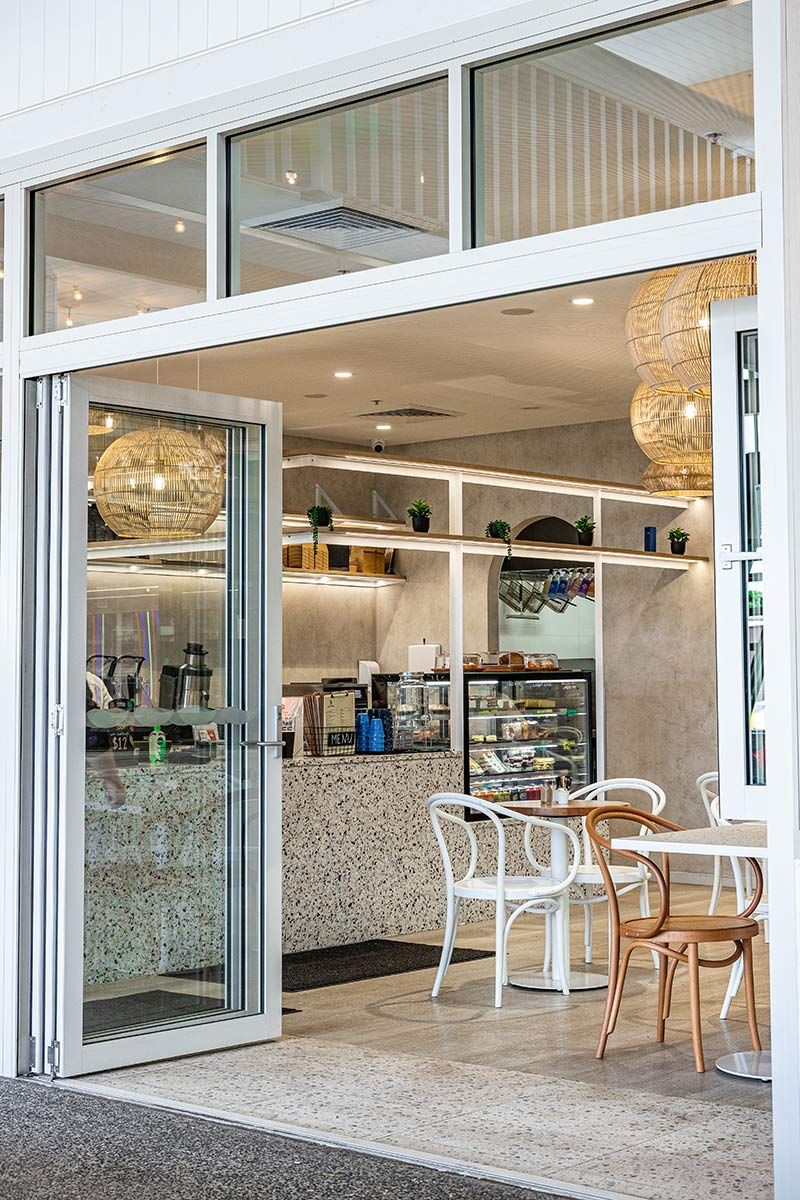 Modern Cafe Interior With White Chairs and Tables — JMB Electrical Services In Port Kembla, NSW