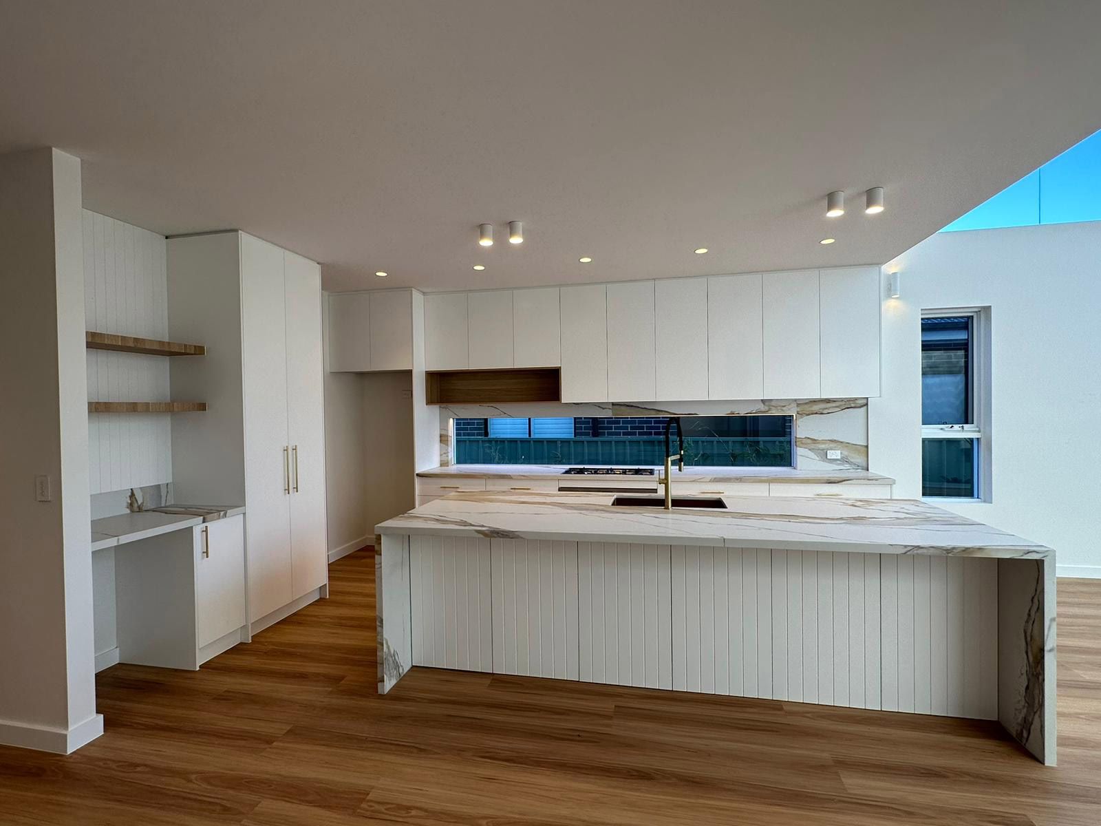 Sleek Modern Kitchen With White Cabinets and Marble Island — JMB Electrical Services In Port Kembla, NSW