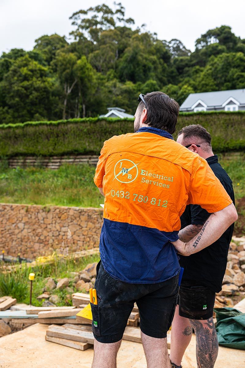 Two Workers Stand Outdoors at a Construction Site — JMB Electrical Services In Port Kembla, NSW