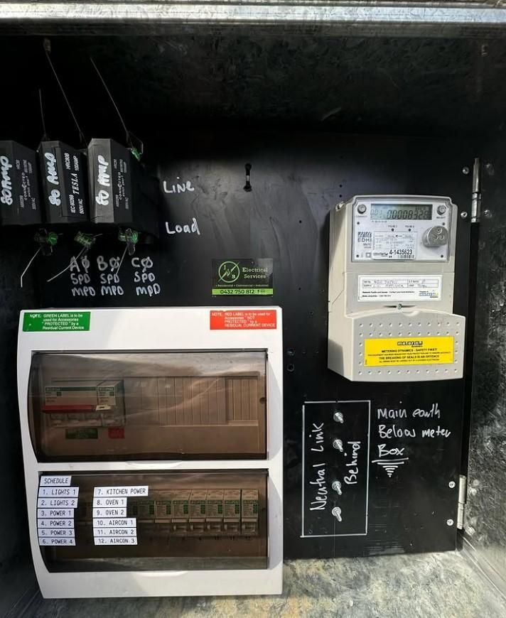 A Black Wall With Electrical Boxes and a Meter on It — JMB Electrical Services In Port Kembla, NSW 