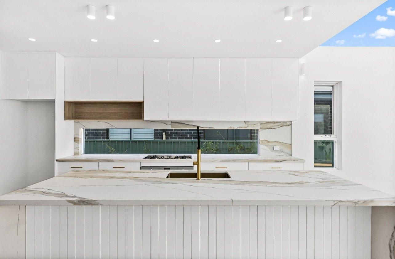A Kitchen With White Cabinets, a Sink, and a Window — JMB Electrical Services In Port Kembla, NSW 