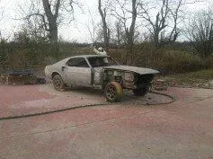 A white car is sitting on a red concrete surface in a parking lot.